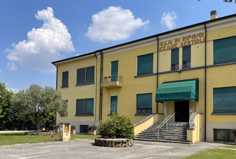 Facciata della sede di due piani dipinta di giallo, con persiane verdi e insegna